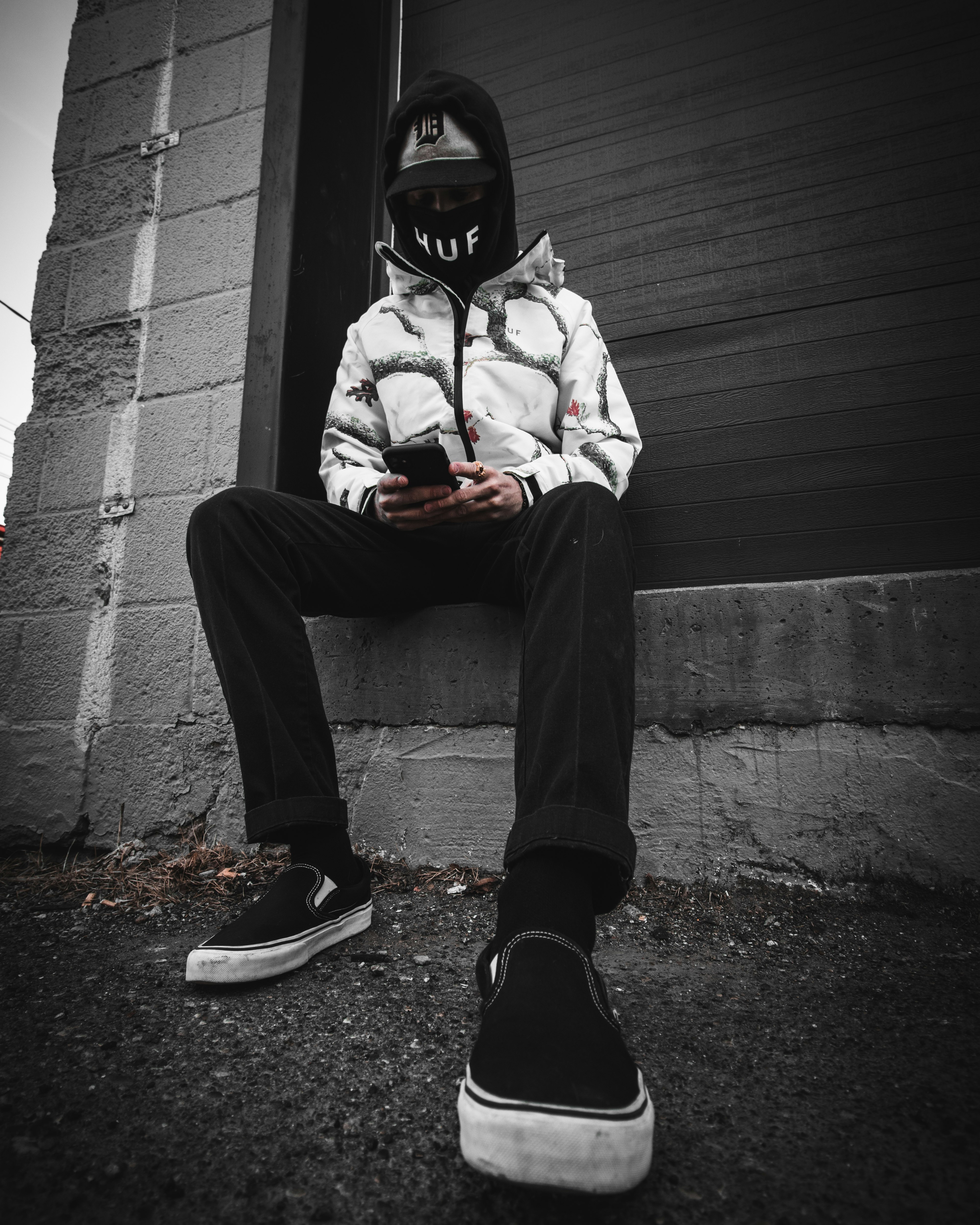 man in white and red hoodie and black pants sitting on gray concrete stairs